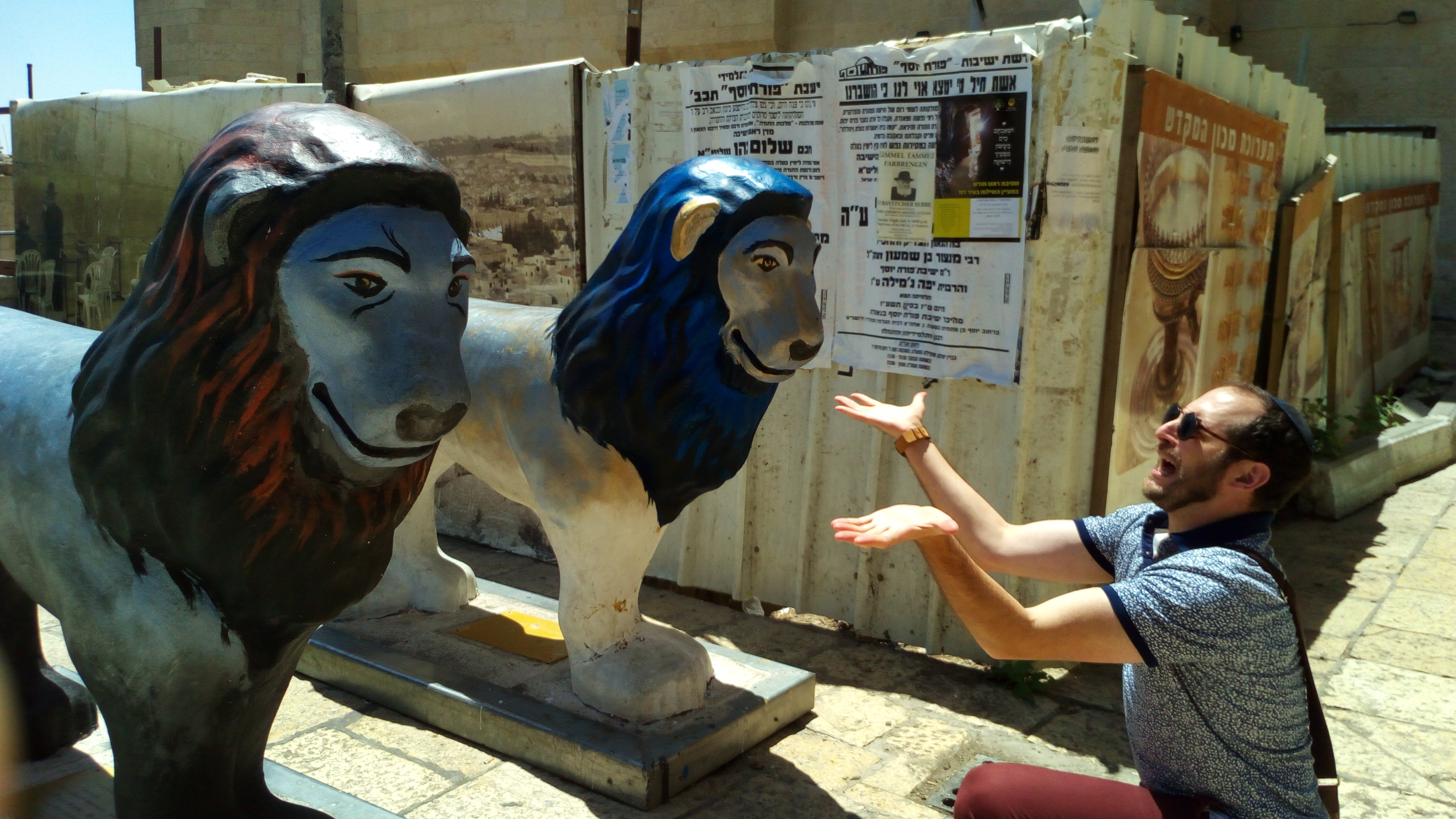 Nachliel Selavan gesturing theatrically at two blue and grey painted lion sculptures