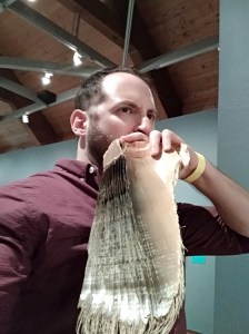 Nachliel Selavan holding a glass fish up beside his face